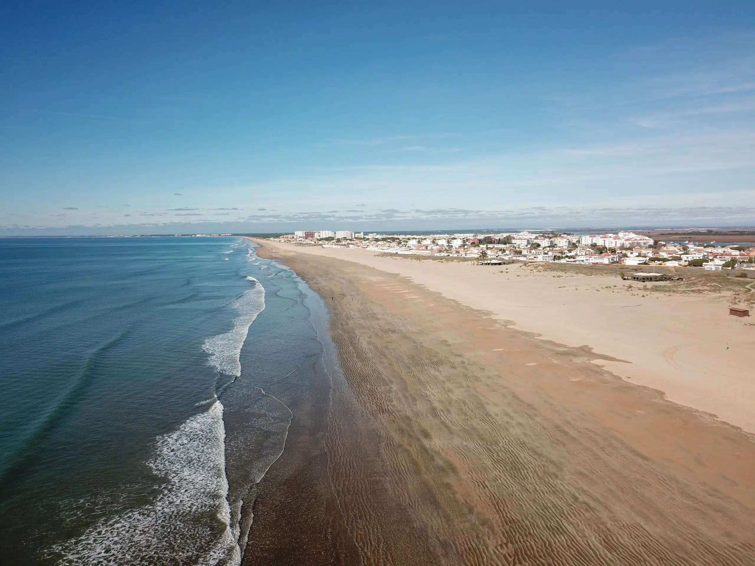 Vista de una playa de Huelva con edificios residenciales en la costa para encontrar un hogar ideal.