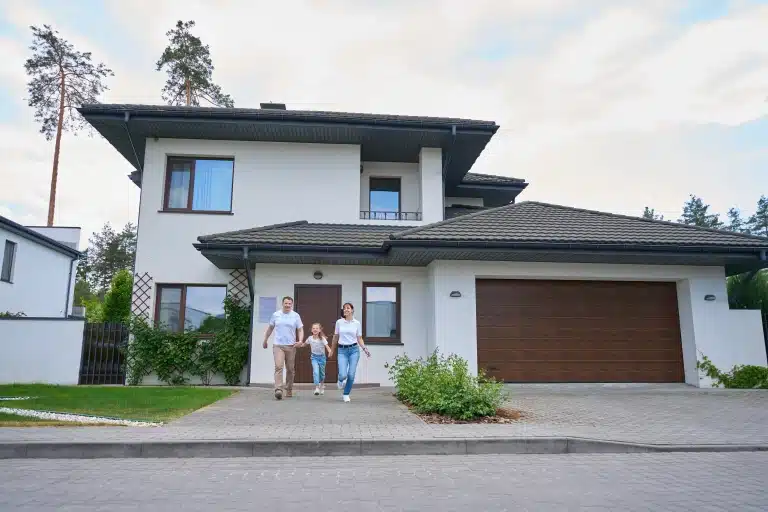 Familia feliz saliendo de su casa ideal, un hogar perfecto gracias a una inmobiliaria en Huelva.