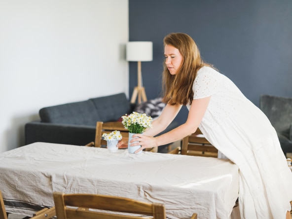 Mujer decorando una mesa con flores, mostrando la preparación de una propiedad para Home Staging en Huelva.